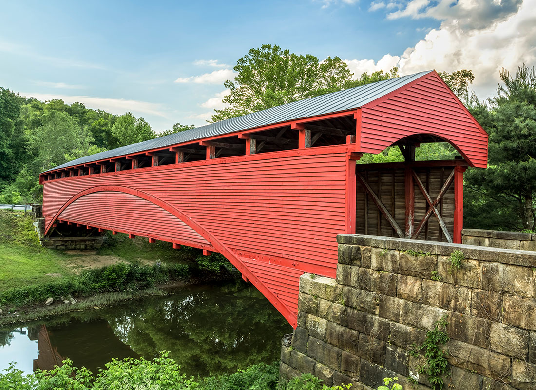 Galion, OH - Red Covered Bridge Crossing a Small River on a Semi Cloudy Day